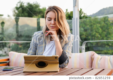 Charming young business lady sitting at the table with tablet Charming young business lady sitting at the table with tablet 82851259