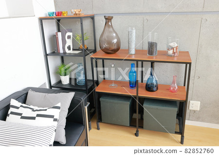 A shelf with a display of glassware and a black sofa 82852760