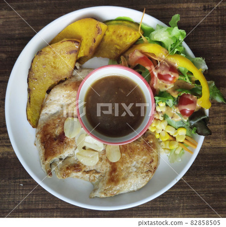 Overhead view of homemade toast and Sliced Grilled organic Chicken meat, steak serving with bread and colorful salad pumpkin and gravy sauce on white plate on wooden table, One famous healthy meal of Overhead view of homemade toast and Sliced Grilled organic Chicken meat, steak serving with bread and colorful salad pumpkin and gravy sauce on white plate on wooden table, One famous healthy meal of 82858505