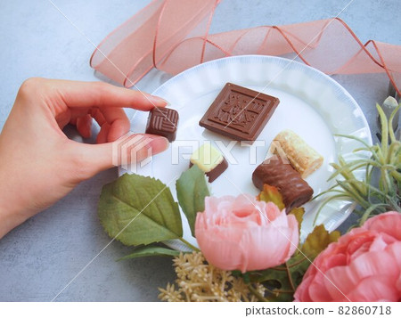 A woman's hand holding chocolate on a plate A woman's hand holding chocolate on a plate 82860718