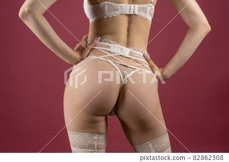 Beautiful young woman in white lace underwear of the bride posing with her back Beautiful young woman in white lace underwear of the bride posing with her back 82862308
