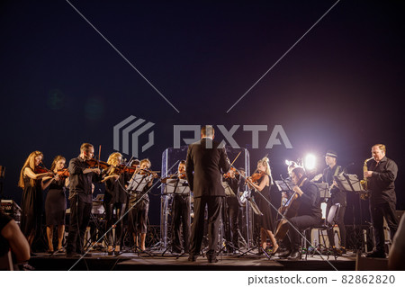 Orchestra performing live concert under blue night sky 82862820