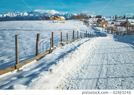 Deep snowy landscape and Pestera village with mountains in background 82863248