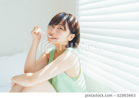 Woman brushing teeth on the bed 82863663