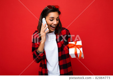 Photo shot of pretty positive surprised young brunet woman isolated over colourful background wall Photo shot of pretty positive surprised young brunet woman isolated over colourful background wall 82864773