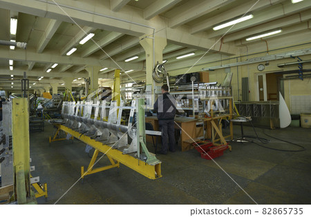 Worker working with a part of a fuselage of light plane at the assembly shop Worker working with a part of a fuselage of light plane at the assembly shop 82865735