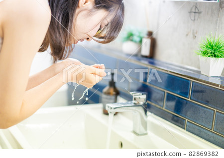 Young woman washing her face in the washroom 82869382