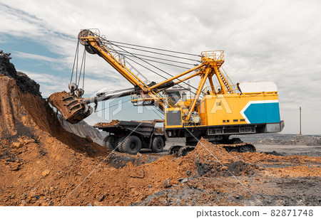 Large quarry dump truck. Big yellow mining truck at work site. Loading coal into body truck. Production useful minerals. Mining truck mining machinery to transport coal from open-pit production 82871748