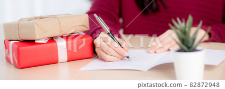 Closeup hand of young asian woman writing postcard in Christmas day at home, eve and celebrate. Closeup hand of young asian woman writing postcard in Christmas day at home, eve and celebrate. 82872948