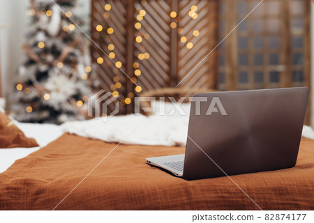 Laptop on the bed in the room Christmas time Laptop on the bed in the room Christmas time 82874177
