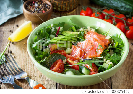 Diet menu, Vegan food. Healthy salad with quinoa, arugula, Tomatoes, Salmon and Avocado on rustic table. 82875402