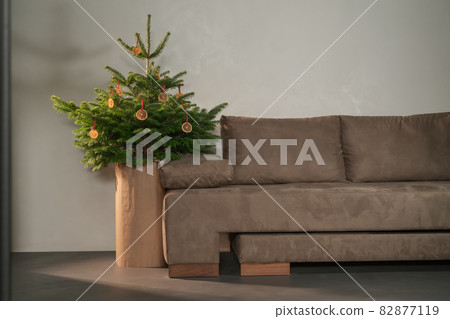 Small christmas tree with natural decorations indoor near couch Small christmas tree with natural decorations indoor near couch 82877119