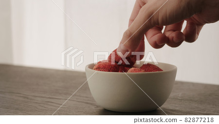 man pick feeze-dried strawberries in white bowl on oak table 82877218