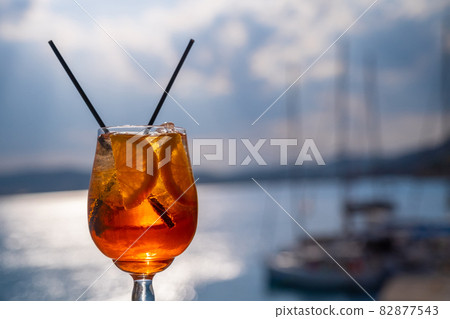 Orange drink or cocktail standing at the little table at the restaurant or cafe with sea background Orange drink or cocktail standing at the little table at the restaurant or cafe with sea background 82877543