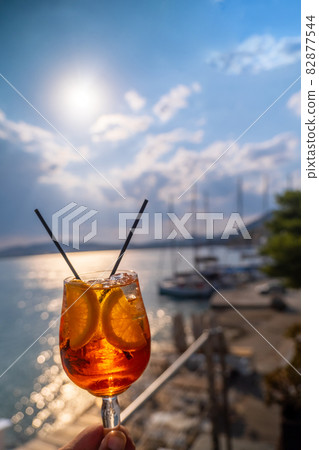 Orange drink or cocktail standing at the little table at the restaurant or cafe with sea background Orange drink or cocktail standing at the little table at the restaurant or cafe with sea background 82877544