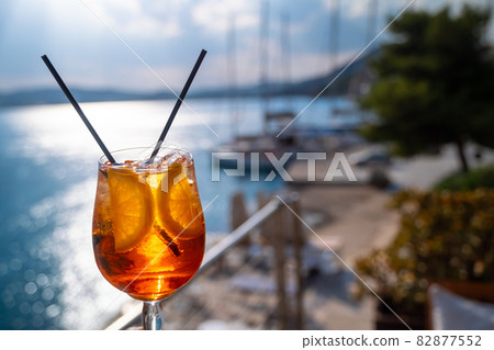 Orange drink or cocktail standing at the little table at the restaurant or cafe with sea background Orange drink or cocktail standing at the little table at the restaurant or cafe with sea background 82877552