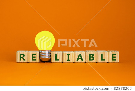 Reliable symbol. Wooden cubes with the word reliable. Yellow light bulb. Beautiful orange background, copy space. Business and reliable concept. 82878203