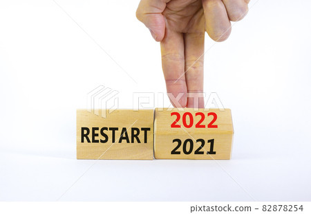 2022 restart new year symbol. Businessman turns a wooden cube and changes words 'Restart 2021' to 'Restart 2022'. Beautiful white background, copy space. Business, 2022 restart new year concept. 82878254