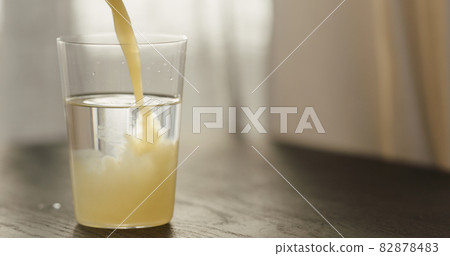 pour orange juice in sparkling water in tumbler glass on black wood table with copy space 82878483