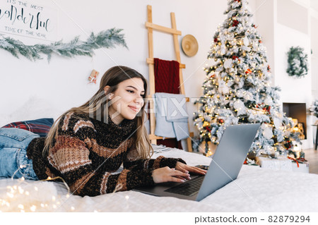 Young caucasian woman using laptop computer in holidays at home in the armchair in living room..Young caucasian woman using laptop computer in holidays at home in the armchair in living room. 82879294
