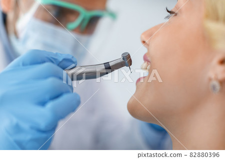Closeup of patient looking at dentist while he drilling tooth 82880396