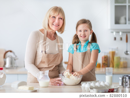 Happy nanny and her granddaughter kneading dough together 82880510