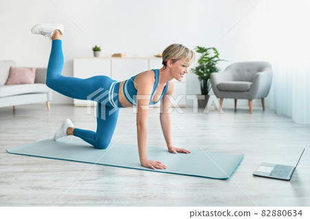 Smiling Woman In Sportswear Doing Donkey Kicks Exercise 82880634