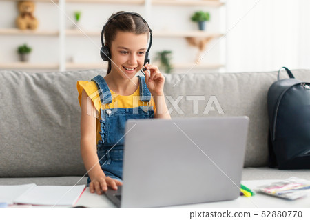 Girl sitting at desk, wearing headphones playing game 82880770