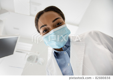 Black Dentist Lady Leaning Over Patient During Check Up In Dental Clinic 82880838