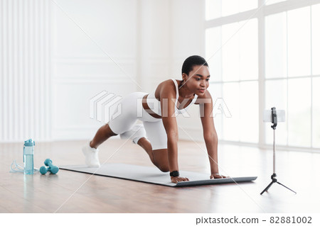 Black Woman Doing Cross Body Mountain Climbers Exercise Using Phone Black Woman Doing Cross Body Mountain Climbers Exercise Using Phone 82881002