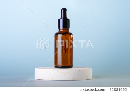 Amber glass dropper cosmetic bottles, white podium on pastel blue background. Scene with geometric shapes. Showcase. Amber glass dropper cosmetic bottles, white podium on pastel blue background. Scene with geometric shapes. Showcase. 82881063