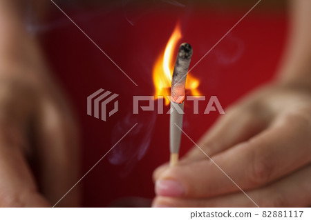 Burning match in hand on red background Burning match in hand on red background 82881117