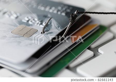 Plastic bank cards and fishing hook on white computer keyboard Plastic bank cards and fishing hook on white computer keyboard 82881143