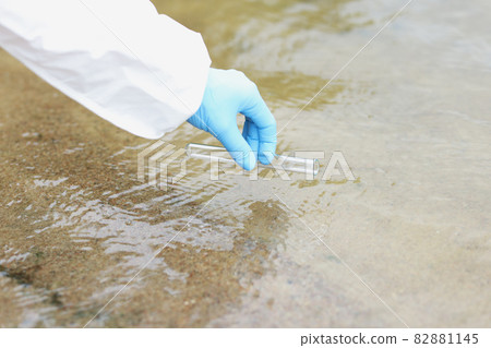Hand of scientist in protective suit and glove makes water intake in lake Hand of scientist in protective suit and glove makes water intake in lake 82881145