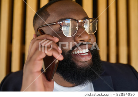A dark-skinned businessman talking on the phone and looking involved 82884050