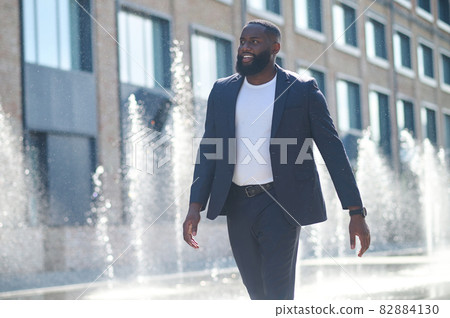 A tall dark-skinned man in a suit in the street 82884130