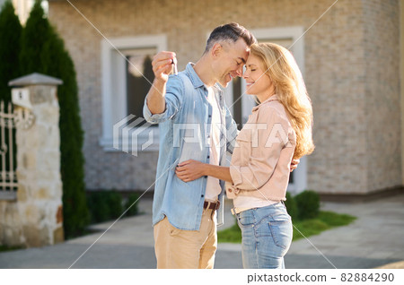Man with key and woman standing with closed eyes Man with key and woman standing with closed eyes 82884290