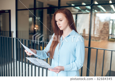 Young serious woman with construction plans in hands Young serious woman with construction plans in hands 82884345
