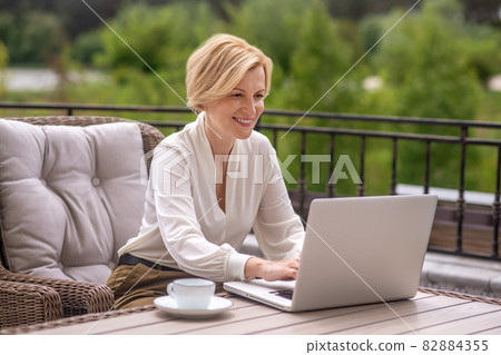 Joyful woman writing an email on the notebook computer Joyful woman writing an email on the notebook computer 82884355