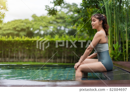 woman sitting on edge of swimming pool woman sitting on edge of swimming pool 82884697