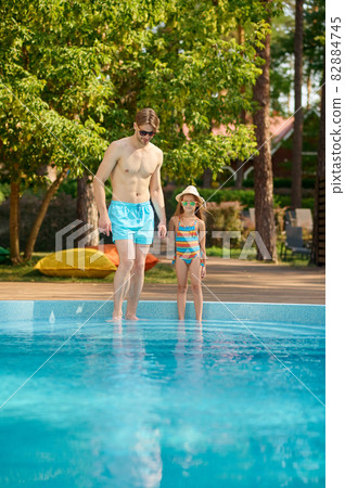A father and a daughter spending time in the swimming pool A father and a daughter spending time in the swimming pool 82884745