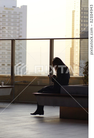 一位女士在屋頂長凳上觸摸智能手機 82884943