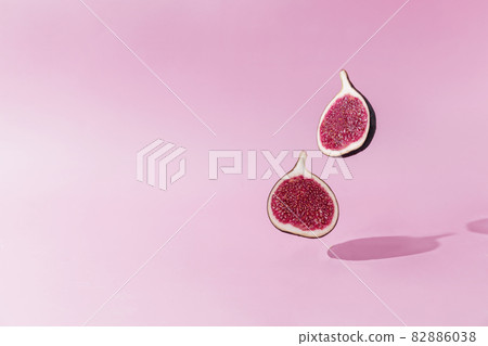 Fresh tasty fig fruit halves levitation with shadow on pink background. Two cross sections of fig falling down or fly. Vegan desert concept. Shadow of flying healthy eating food. High quality photo Fresh tasty fig fruit halves levitation with shadow on pink background. Two cross sections of fig falling down or fly. Vegan desert concept. Shadow of flying healthy eating food. High quality photo 82886038