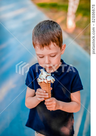 boy eating ice cream in the summer on the street 82886678