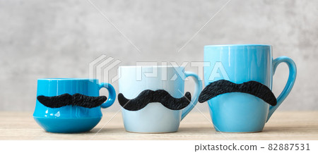 Blue coffee cup and tea mug with Black mustache decor on wood table background in the morning. Blue November, Happy Father day and International men day concept 82887531