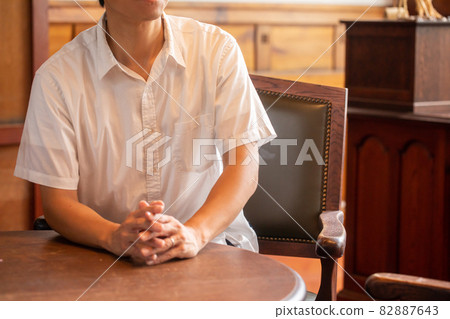 A man who talks with his hands together A person who sits in a chair and talks A man who talks with his hands together A person who sits in a chair and talks 82887643