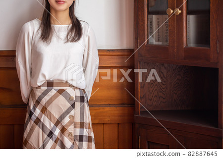 A woman standing next to a shelf, a woman looking straight at the front A woman standing next to a shelf, a woman looking straight at the front 82887645