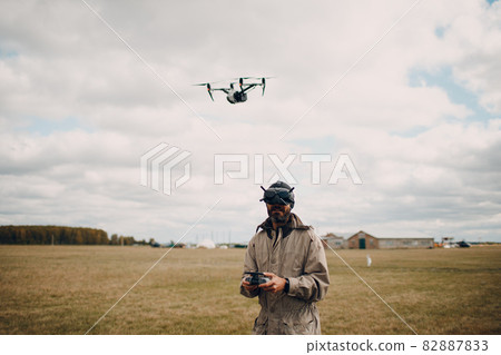 Man controlling fpv quadcopter drone with goggles antenna remote controller Man controlling fpv quadcopter drone with goggles antenna remote controller 82887833