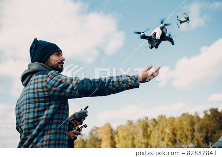 Man pilot controlling quadcopter drone with remote controller pad Man pilot controlling quadcopter drone with remote controller pad 82887841