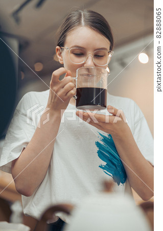 Beautiful young woman smelling coffee in cafeteria Beautiful young woman smelling coffee in cafeteria 82888065